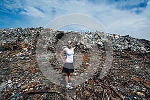Girl standing in front of trash mountain at garbage dump