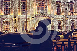 Girl standing with her back to the camera and looking at the christmas lights and enjoys the holiday atmosphere