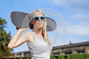 Girl standing and holding skateboard behind her head