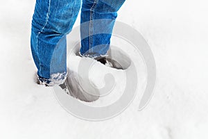 The girl is standing knee-deep in snow in a cold, freezing winter, close-up. The legs of a young girl in a snowdrift. Women`s feet