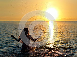 Girl standing in the lake at sunset