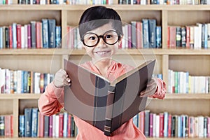 Girl standing in library while reading textbook