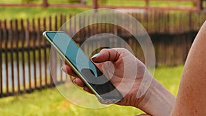 A girl standing in nature with a smartphone in her hands watching messages or news