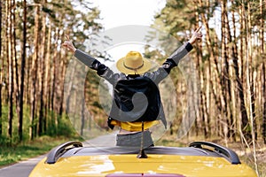 Girl Standing out of Yellow Car Sunroof Back View