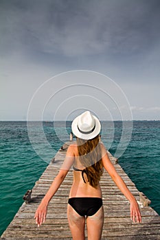 Girl standing at the pier enjoying the breeze from the sea