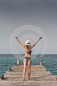 Girl standing at the pier raising her arms to the sky