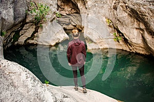 Girl standing on the rock looking at the little blue pond