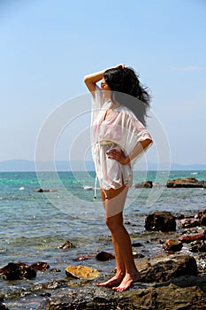 Girl standing on rocks near the sea.