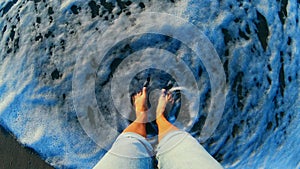 Girl standing on sandy beach. Sea ocean wave with white foam rolls