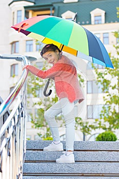 Girl standing on stairs and holding umbrella. Autumn rain. Waiting for bad weather under umbrella. Stylish girl in