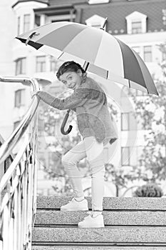 Girl standing on stairs and holding umbrella. Autumn rain. Waiting for bad weather under umbrella. Stylish girl in