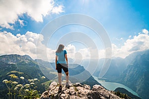 Girl standing on the top of a cliff watching a beautiful mountain scenery in the bavarian Alps