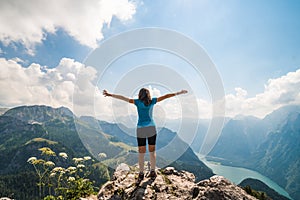 Girl standing on the top of a cliff watching a beautiful mountain scenery in the bavarian Alps