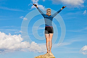 Girl is standing on top of the rock and enjoys sun