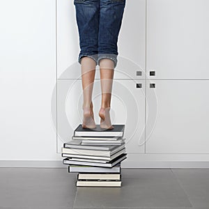 Girl standing on top of a stack of books