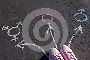 Girl Standing With Transgender, Male And Female Gender Symbols Drawn On Asphalt Road. Overhead view