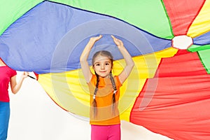 Girl standing under parti-colored parachute canopy