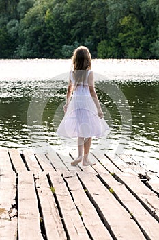 A girl standing on a wooden pier, View from the back