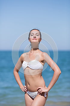 Girl stands with arms akimbo against the sea
