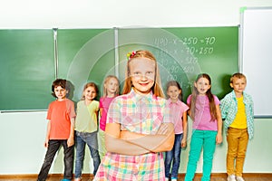 Girl stands with arms crossed near blackboard