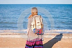A girl stands back and looks at the sea. Hippie Girl looks at the sea. Woman with a bottle of wine is by the sea. hippie