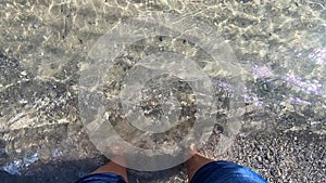 Girl stands bare feet on sandy beach and buries its fingers in sand