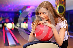 Girl stands and bases on ball in bowling club