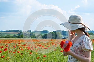 A girl stands in a blooming field of poppies, cornflowers