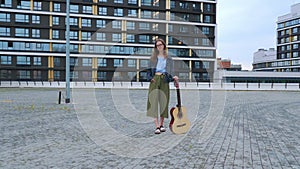 Girl stands with classical guitar in square