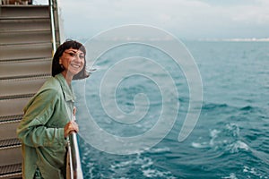 girl stands on the deck of a cruise ship. The girl is traveling. A young beautiful brunette travels on a yacht