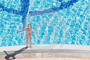 A girl stands on the edge of the pool