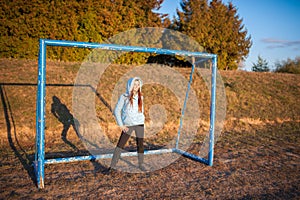 The girl stands at the football goal. brunette girl stands on the goal of football
