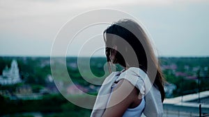 The girl stands on a high roof and looks into the distance. My hair is blowing in the wind