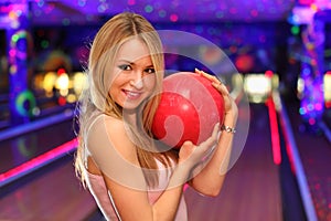 Girl stands and hugs ball in bowling club