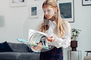 Girl stands and leafs through a textbook