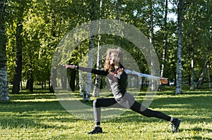 Girl stands in the pose of a warrior, girl in a  black jacket, sports, yoga in the Park