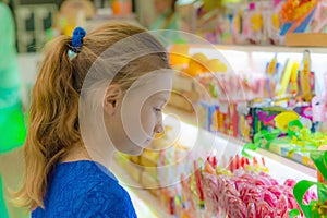 A girl stands at the shop window and looks at sweets and sweets
