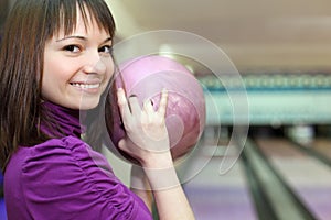 Girl stands sideways and smiles with ball in hands