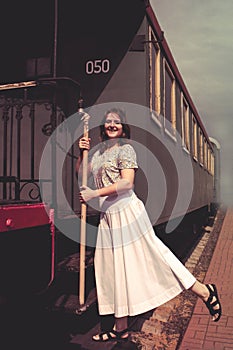 A girl stands on the steps of the cars train. Vintage train is at the station ÑˆÑ‚ smoke, embarkation or disembarkation of the