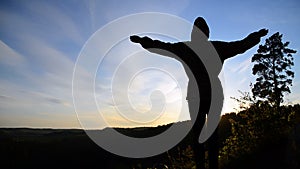 A girl stands on top of a mountain with her hands open. Freedom in the gesture.