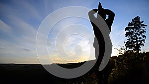 A girl stands on top of a mountain with her hands open. Freedom in the gesture.