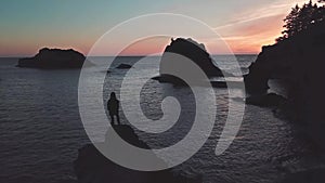 Girl stands on top of sea stack of Oregon coast watching twilight