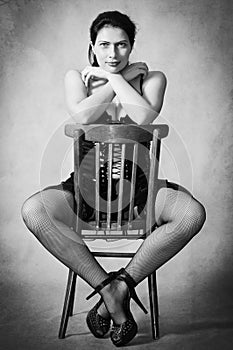 Girl in stockings sitting astride a chair