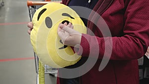 Girl in store buys funny pillow in form of yellow smiley face for car seat