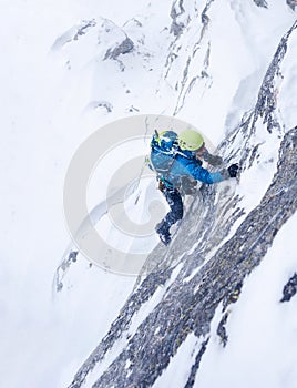 Girl in the storm during an extreme winter climb. West italian A