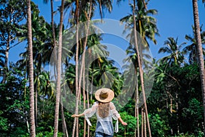 Girl in straw against the background of tropical coconut trees and blue sky. Walk in the Rainforest on the island of Koh
