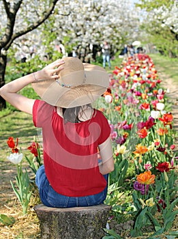 girl with straw boater hat in the field of Tulips flowers