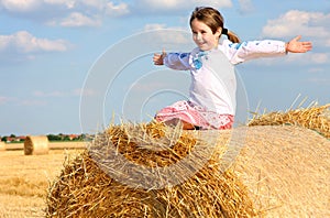 Girl on the straw after harvest field