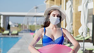 Girl in straw hat keep precautions wears medical mask for protection virus and infection holds swimming ring in his