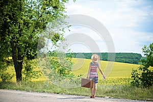 Girl in straw hat with retro suitcase near summer